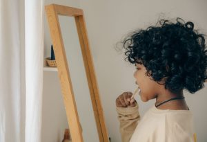 a kid brushing their teeth before they floss